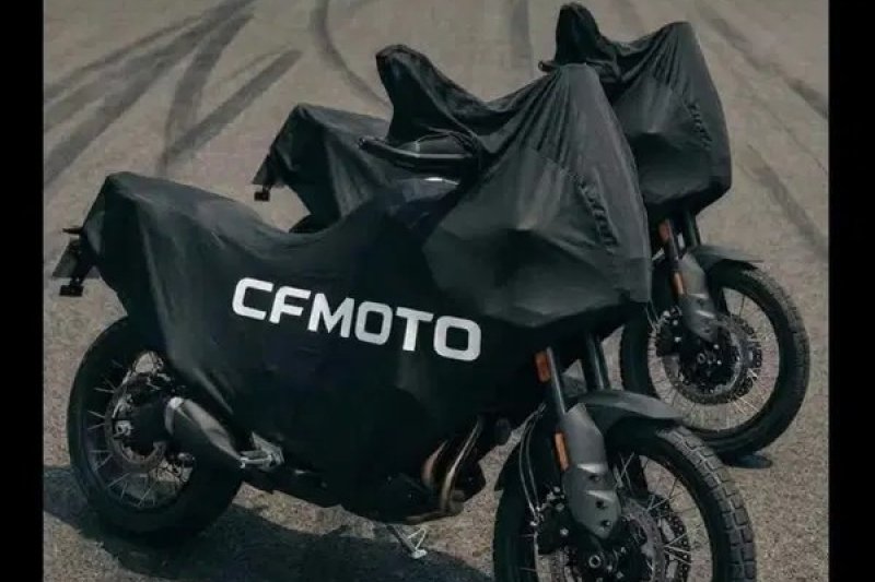 Duas unidades da CFMOTO 550MT cobertas por capas pretas com a marca, em piso de asfalto