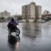Motociclista de capa de chuva em avenida molhada da cidade