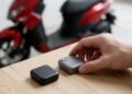 Mão escolhendo entre dois rastreadores com uma moto desfocada ao fundo