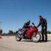 Iniciante e instrutor ao lado de moto vermelha, como fazer curva de moto