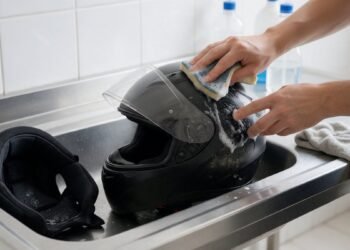 Pessoa limpando a viseira do capacete na pia, como limpar a viseira do capacete
