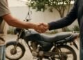 Aperto de mãos entre comprador e vendedor ao lado de uma moto usada