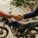 Aperto de mãos entre comprador e vendedor ao lado de uma moto usada