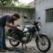 Homem inspeciona o motor de uma moto usada antes de comprar moto usada