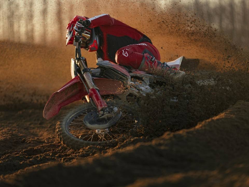 Piloto contorna curva de terra com a Ducati Desmo450 MX, levantando poeira