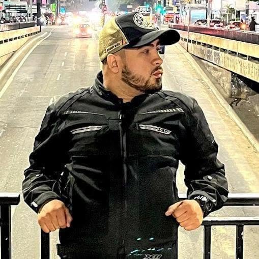 Eric Vieira, de jaqueta de motociclista, em uma avenida de São Paulo à noite