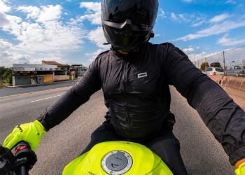 Eric Vieira pilotando a Yamaha MT-03 verde-neon, de capacete preto, luvas amarelas e jaqueta preta, com equipamentos para motociclistas