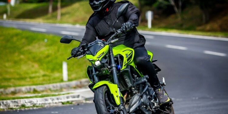 Yamaha MT-03 verde-neon inclinada em uma curva de estrada, pilotada por Eric Vieira