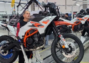 Operário prepara KTM 390 Adventure suspensa na linha de montagem da fábrica da KTM em Manaus
