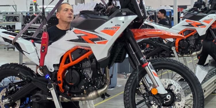 Operário prepara KTM 390 Adventure suspensa na linha de montagem da fábrica da KTM em Manaus
