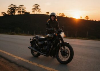 Mulher motociclista sorri ao lado da moto numa estrada ao pôr do sol, para frases de moto feminina