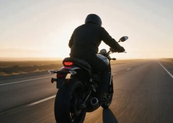 Motociclista pilotando em estrada aberta rumo ao horizonte ao amanhecer