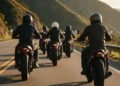 Grupo de motociclistas de capacete em fila numa estrada de serra, cenário para frases para motoqueiros