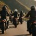 Grupo de motociclistas de capacete em fila numa estrada de serra, cenário para frases para motoqueiros