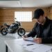 Motociclista consultando o glossário do seguro de moto com papéis na mesa