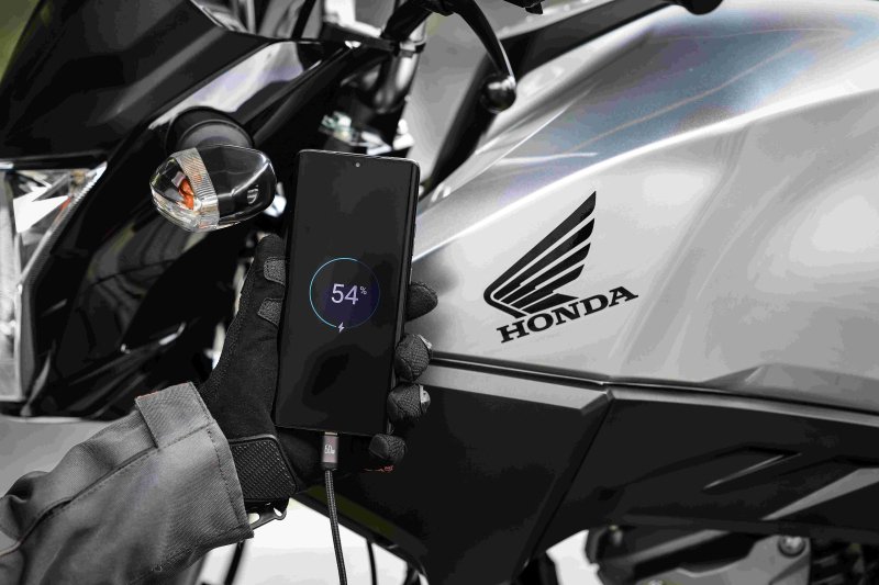 Tomada USB-C no punho da Honda CG 160 2027 carregando um celular