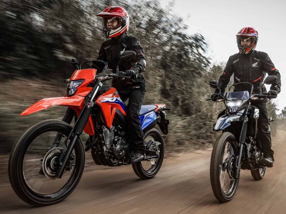 Duas Honda XR300L Tornado 2027, vermelha e preta, rodando em estrada de terra