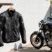 Jaqueta de motociclista com proteções pendurada ao lado de uma moto