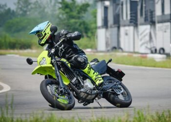 Kawasaki KLX300SM 2027 inclinada em curva em pista de asfalto