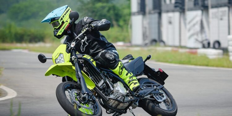 Kawasaki KLX300SM 2027 inclinada em curva em pista de asfalto