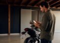 Pessoa usando o celular ao lado da moto para emitir o documento digital