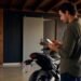 Pessoa usando o celular ao lado da moto para emitir o documento digital