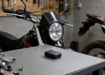 Rastreador GPS preto sobre bancada ao lado de uma moto, melhor rastreador para moto