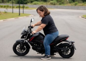 Mulher de baixa estatura apoiando os pés no chão sentada em uma moto