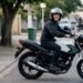 Iniciante sorrindo de capacete sentado em uma moto popular