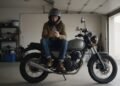 Motociclista de capacete olhando o celular depois de pensar: não consigo financiar uma moto