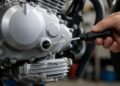 Mão verificando o nível de óleo do motor da moto com a vareta