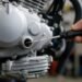 Mão verificando o nível de óleo do motor da moto com a vareta