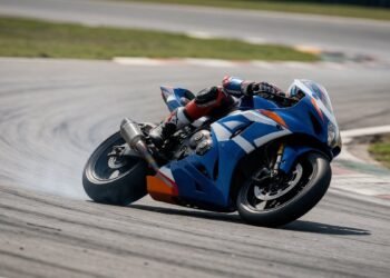 Piloto em moto de corrida azul e branca em curva, onde assistir MotoGP