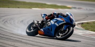 Piloto em moto de corrida azul e branca em curva, onde assistir MotoGP