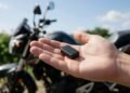 Mini rastreador na mão diante de uma moto, onde esconder rastreador na moto