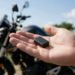 Mini rastreador na mão diante de uma moto, onde esconder rastreador na moto