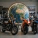 Motos de estilos diferentes alinhadas diante de um globo terrestre, para ilustrar a origem das marcas de moto