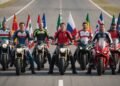 Motociclistas de vários países ao lado de suas motos e bandeiras na pista