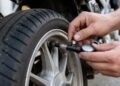 Mãos calibrando o pneu de uma moto com calibrador