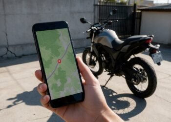 Mão segurando celular com mapa e moto ao fundo, rastreador de moto pelo celular