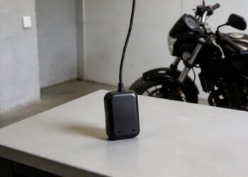 Rastreador preto sobre mesa com moto ao fundo, rastreador com bateria própria