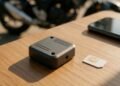 Rastreador, chip e celular sobre mesa de madeira, rastreador para moto sem mensalidade