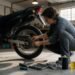 Pessoa agachada fazendo a revisão básica da corrente da moto na garagem