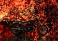 Royal Enfield Classic 650 Hypershift 125th Anniversary Edition de lado, diante de fundo de faíscas alaranjadas