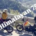 Duas Royal Enfield Himalayan 750 sem camuflagem, uma vermelha e outra branca com grafismos, paradas à beira de estrada de montanha