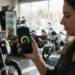 Mulher olha no celular o medidor de score para financiar moto, em uma loja de motos