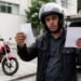 Motociclista comparando duas propostas em papel ao lado da moto