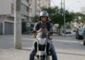 Motorista de aplicativo em cima da moto olhando o celular, representando seguro de moto para aplicativo
