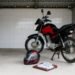 Moto de uso diário guardada em garagem simples com capacete e documentos, seguro de moto Suhai