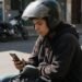 Financiamento de moto simulação feita no celular por uma pessoa de capacete com a moto ao fundo